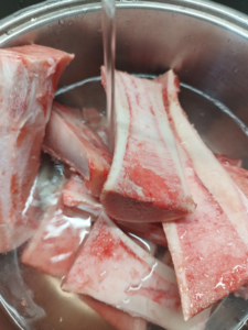 Beef bones should be washed with cold water. Photo of the procedure.