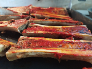 Photo showing beef bones that were baked for 30 min and then are covered with tomato paste.