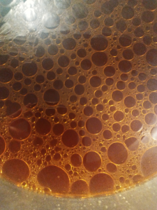 The brown beef stock after straining. One can see the fat that is floating on top.